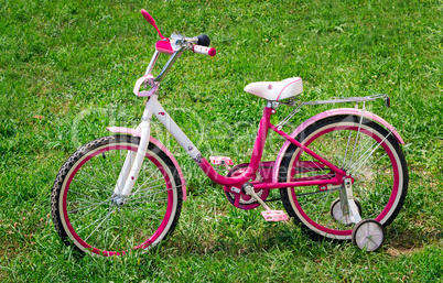 The bicycle for the girl on a green lawn.