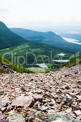 Jagged rubble of rocks against green hills in fog