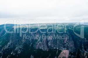 Large steep cliffs and plateau under overcast sky and fog