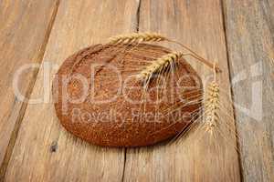 bread and ears of wheat on the wooden table