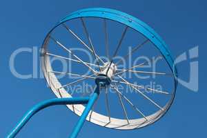 Metal detail as a bicycle wheel against the sky