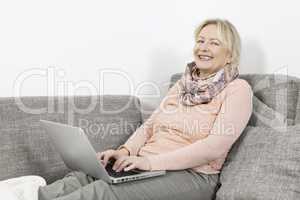 Frau mit Laptop auf Sofa