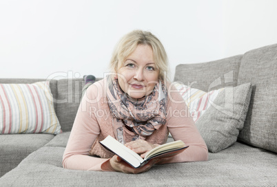 Frau liest Buch auf Sofa