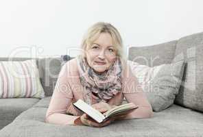 Frau liest Buch auf Sofa
