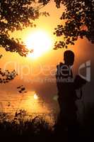 Photographer at the lake in front of the setting sun