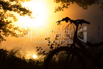 Bike on the lake in front of the setting sun