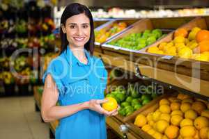 Portrait of a smiling woman picking orange