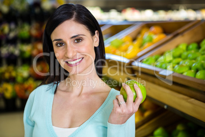 Portrait of a smiling woman picking apple