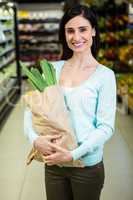 Pretty smiling woman holding grocery bag