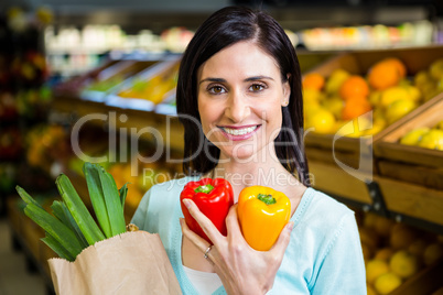 Smiling woman holding pepper and grocery bag