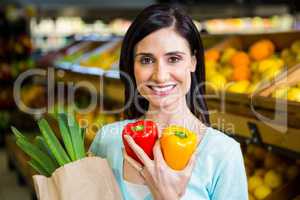 Smiling woman holding pepper and grocery bag