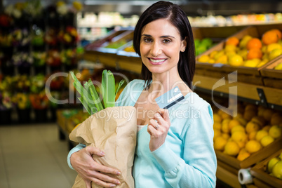 Smiling woman holding credit card and grocery bag