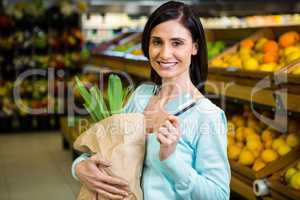 Smiling woman holding credit card and grocery bag