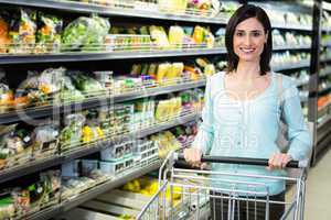 Smiling woman pushing trolley in aisle