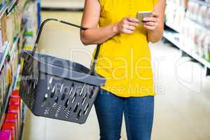 Woman with basket using her smartphone