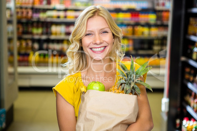 Smiling woman standing in aisle with grocery bag