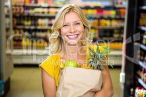 Smiling woman standing in aisle with grocery bag