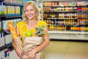 Smiling woman standing in aisle with grocery bag