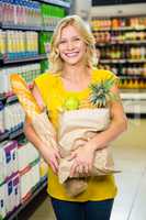 Smiling woman standing in aisle with grocery bag