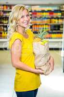 Smiling woman standing in aisle with grocery bag