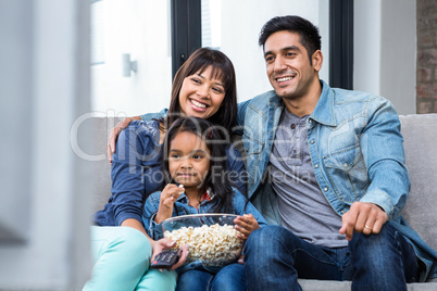 Smiling family eating popcorn while watching tv