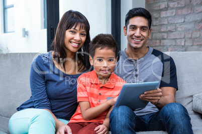 Smiling family using tablet on the sofa