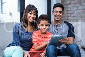 Smiling family using tablet on the sofa