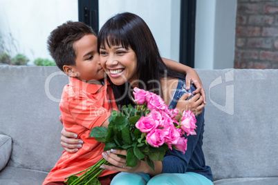 Cute son hugging his mother after giving her flowers