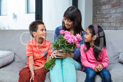 Happy mother holding roses sitting with her son and daughter on