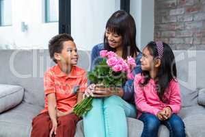 Happy mother holding roses sitting with her son and daughter on