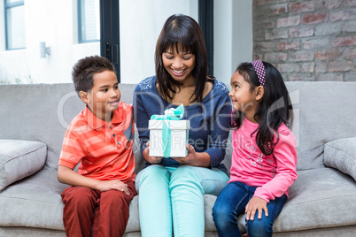 Happy mother holding a present and sitting with her children