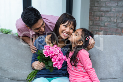 Happy mother holding roses being kissed by her daughter