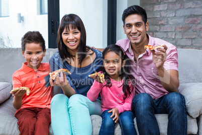 Happy family eating pizza on the sofa
