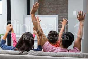Happy family rejoicing while watching tv on the sofa