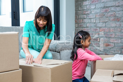 Happy mother and daughter opening boxes