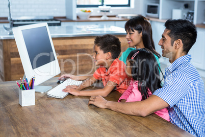 Happy family using computer in kitchen