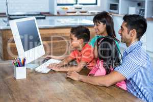 Happy family using computer in kitchen