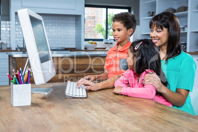 Happy mother using computer with her children