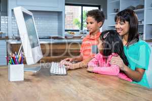 Happy mother using computer with her children