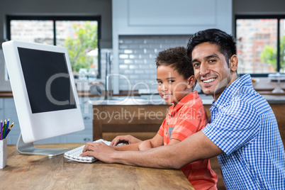 Smiling father using computer with his son