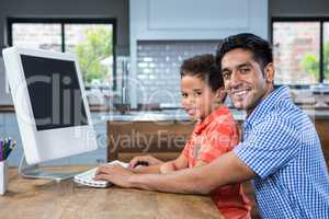 Smiling father using computer with his son