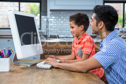 Smiling father using computer with his son