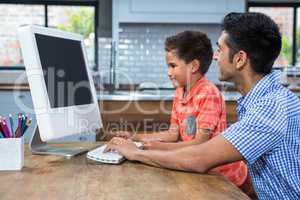 Smiling father using computer with his son