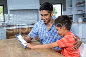 Smiling father using tablet with his son