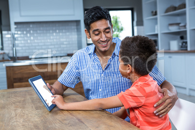 Smiling father using tablet with his son