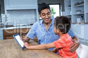 Smiling father using tablet with his son