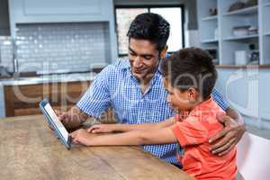 Smiling father using tablet with his son