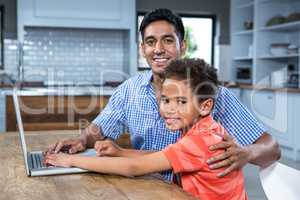 Smiling father using laptop with his son