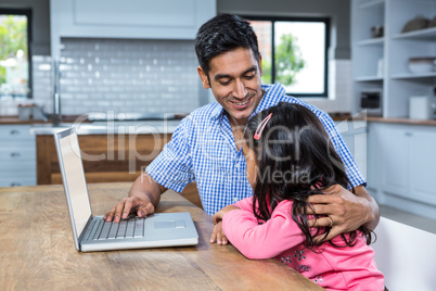 Smiling father using laptop with his daughter