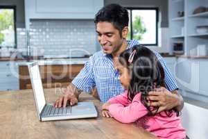 Smiling father using laptop with his daughter